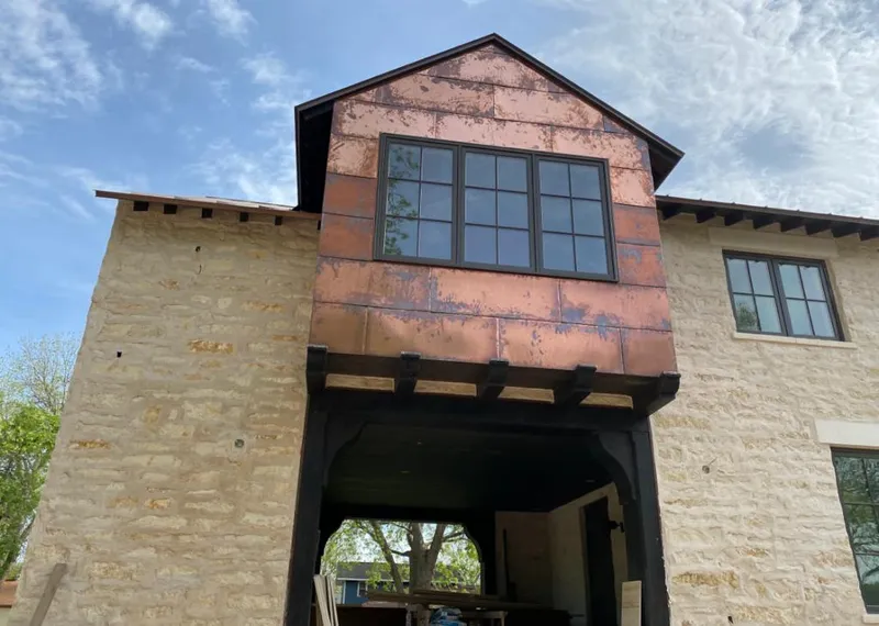 Copper metal panel facade on a stone building for Skylight Installation in Pella
